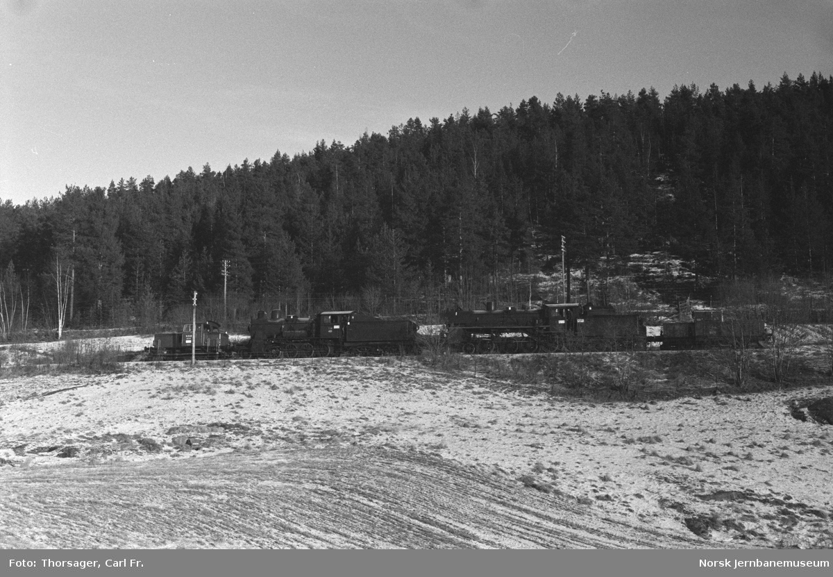 Skiftetraktor Skd 220 170 og Skd 214 84 (nærmest) med damplokomotivene 26c 411 og 24b 236 mellom Sysle og Snarum stasjoner. Toget er underveis til Kløftefoss på Krøderbanen