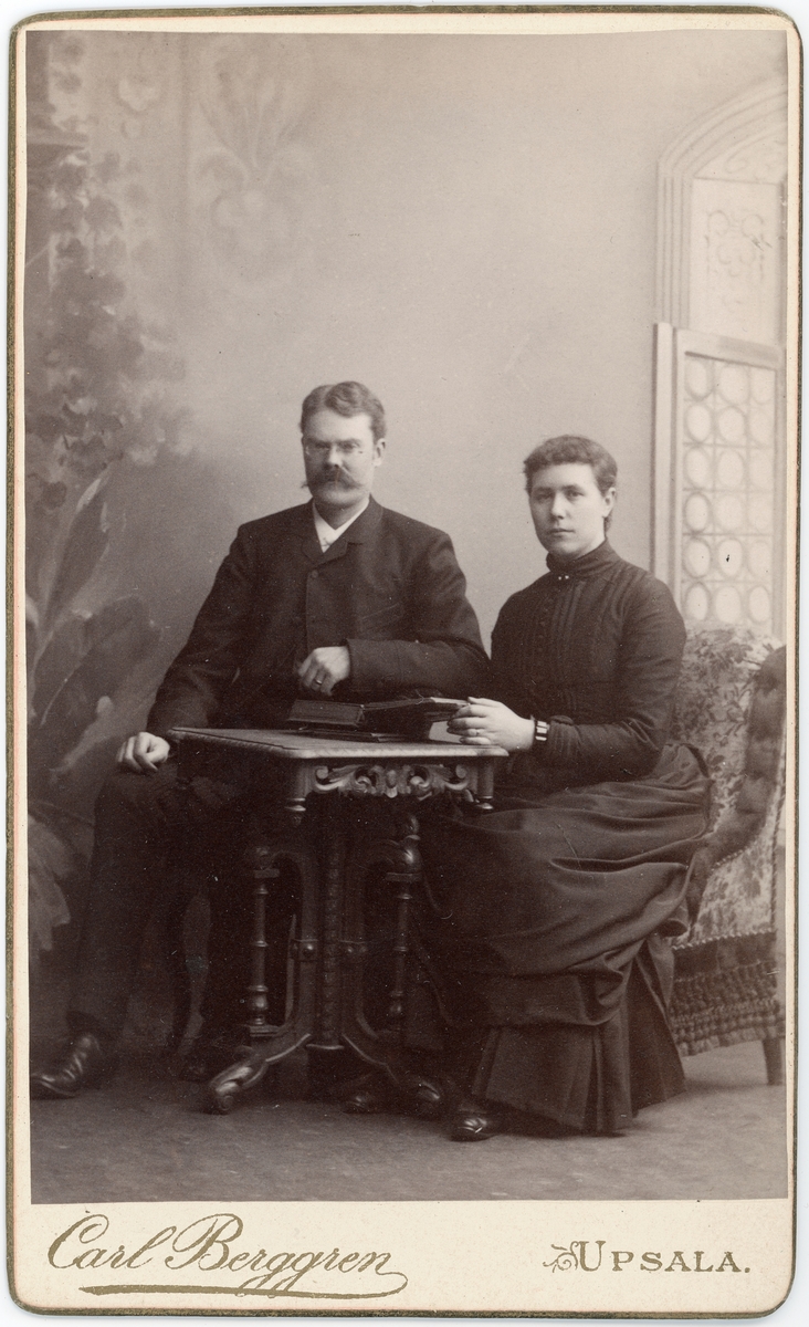 Kabinettsfotografi - man och kvinna sitter vid bord, Uppsala 1888
