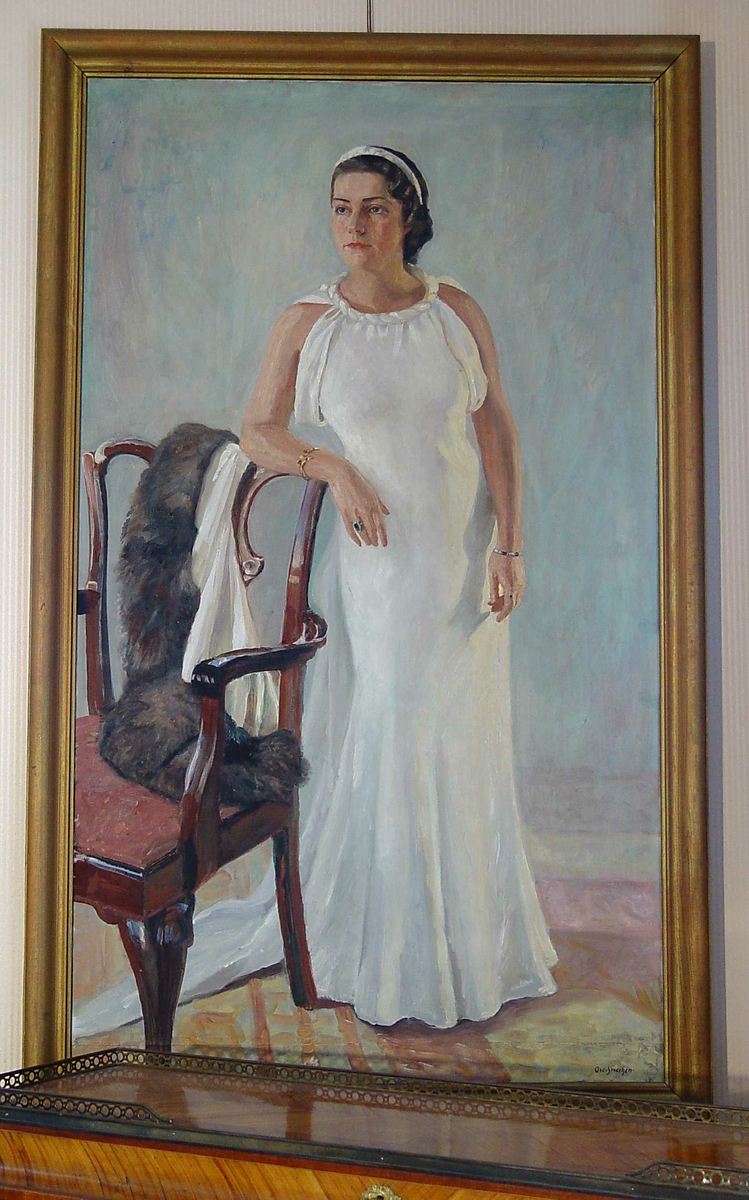 Maleri av kvinne i helfigur, hvilende med en arm på stolrygg. Kvinne kledd i hvit aftenkjole.