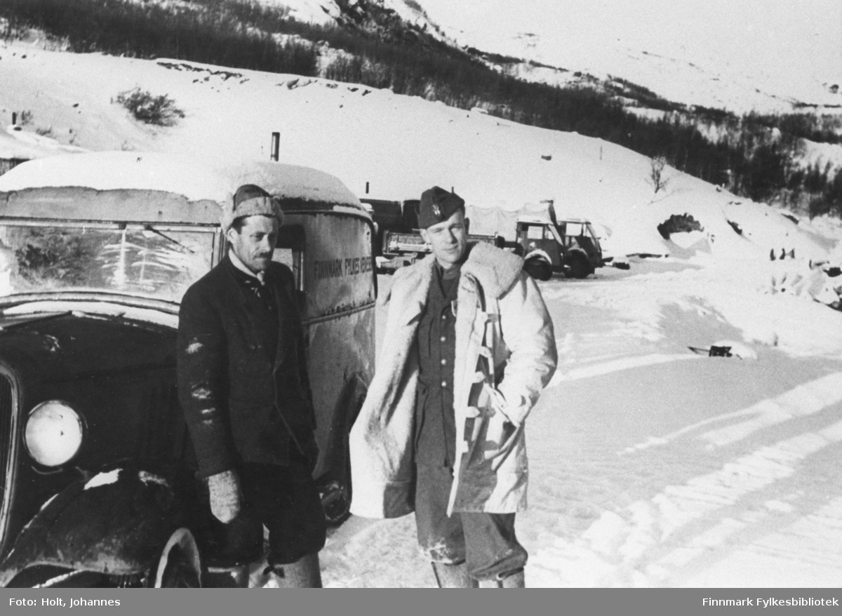 Avd. ingeniør Johannes Holt til høyre, ca. 1946 i et sted i Finnmark. Varebilen kan være en Chevrolet 1934-35-modell på lett lastebilchassis. Karosseriet er norskbygd. Det står trolig FINNMARK FYLKES VEGVESEN på siden. I bakgrunnen tyske etterlatenskaper: to franskbygde lastebiler (kanksje Matford?). 
