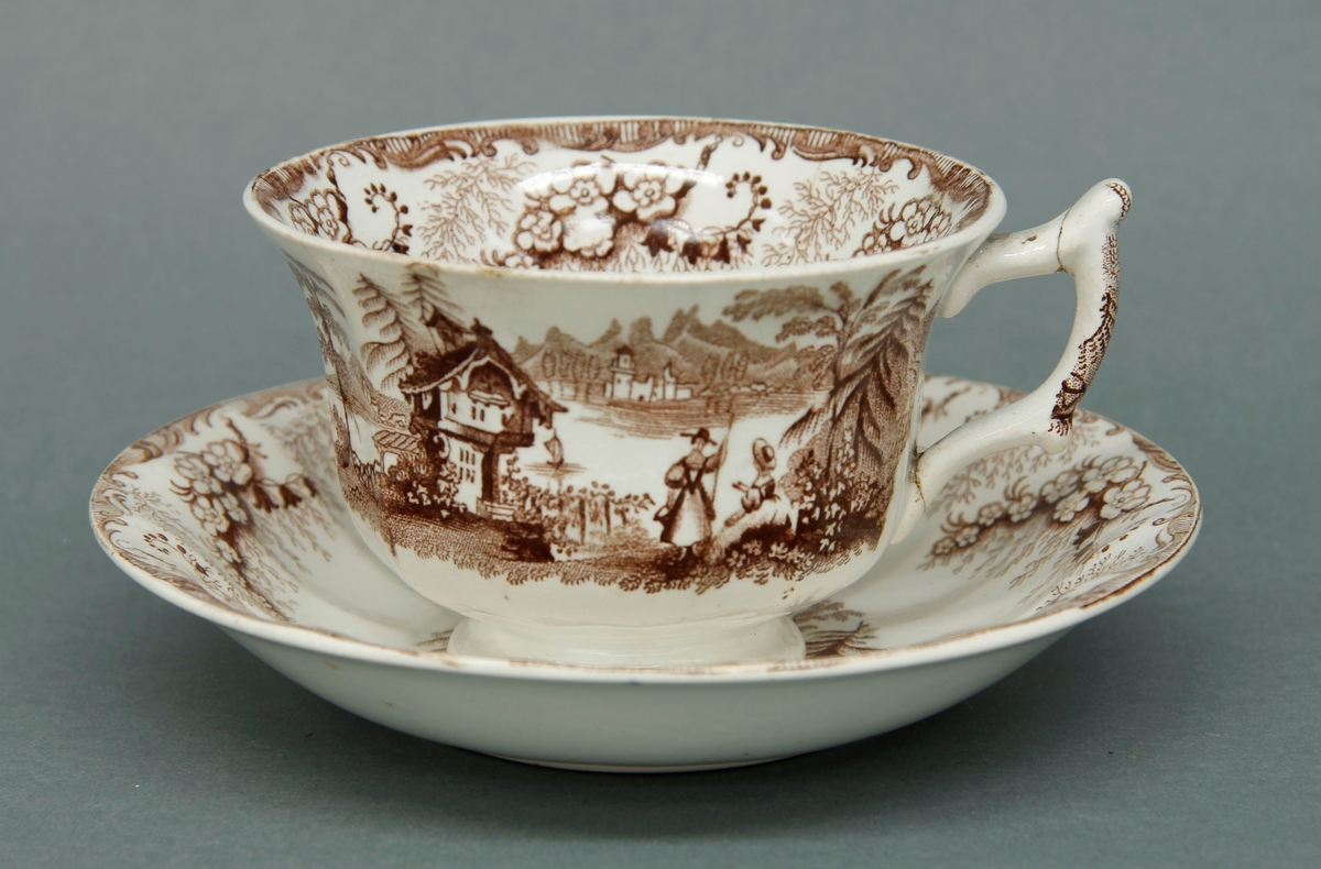 Kopp og skål med påtrykket dekor i brun tone. Alpeinspirert motiv. Del av te- og kaffeservise i 10 deler: Kaffekanne, tekanne og åtte kopper med skåler.
