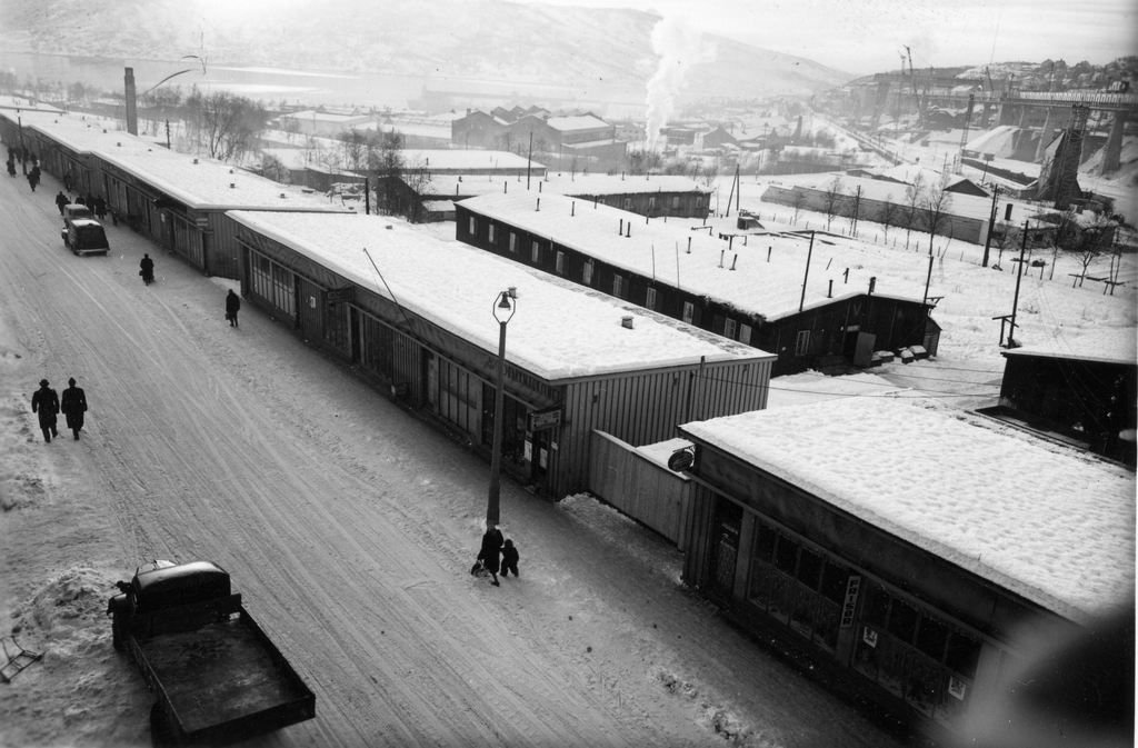 Forretningsbrakkene i Kongens gate. Bak forretningsbrakkene ligger en tysk millitærleir som etter krigen ble brukt til boliger for husløse i Narvik.