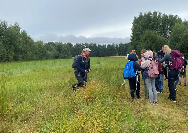 Foto av naturveileder som forteller en gruppe elever om naturen ute i naturreservatet