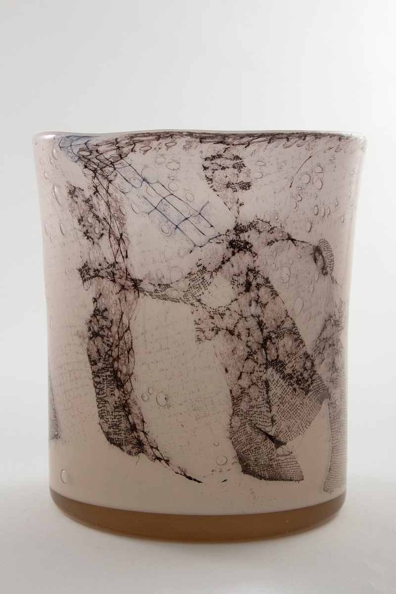 Høyreist ovalformet vase i grårosa glass med innlagt dekor av metallnett. Dekoren fremstiller stiliserte kvinnefigurer i en dansende bevegelse. Øvre del er svakt konisk og har en ujevn formet munningsrand.