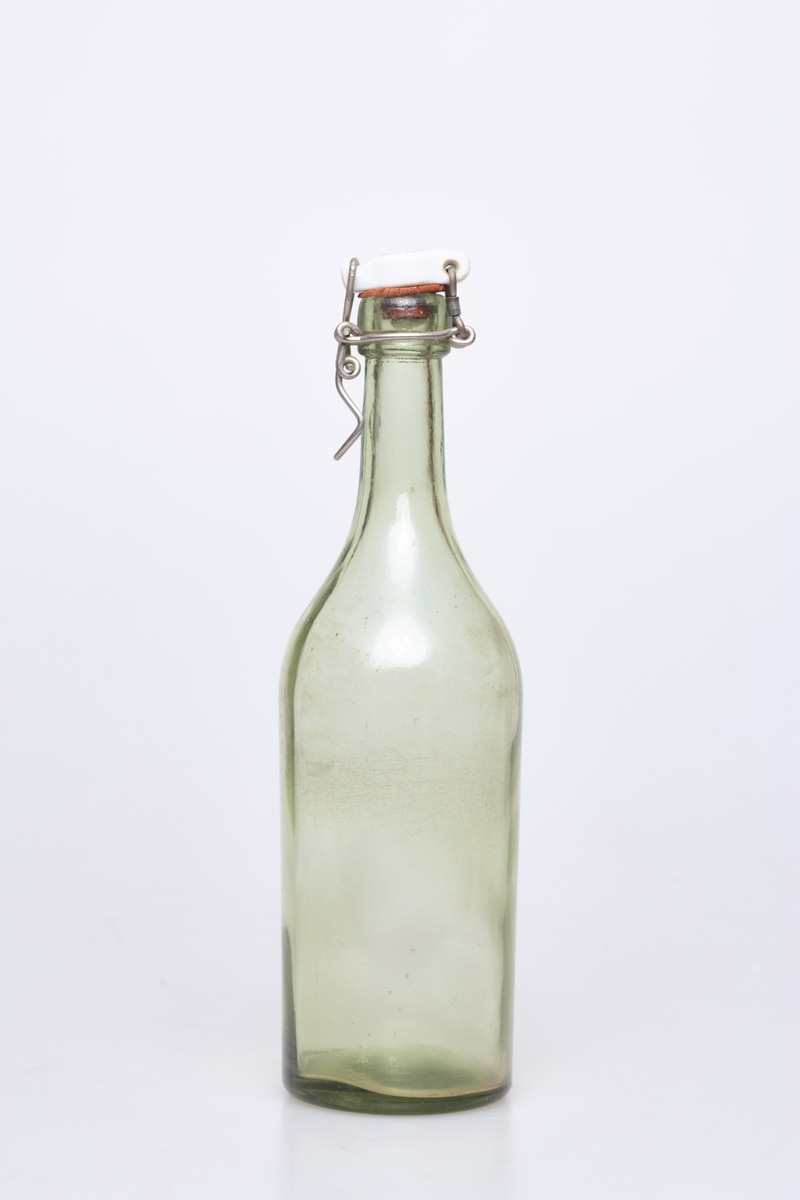 Glassflaske av klart glass med noe grønnskjær. Har hvit plastkork med metallfeste.
