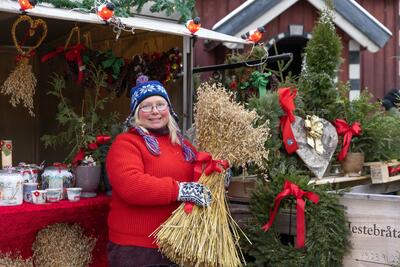 Bildet viser en kvinne foran markedsboden sin som holder frem et julenek (Foto/Photo)