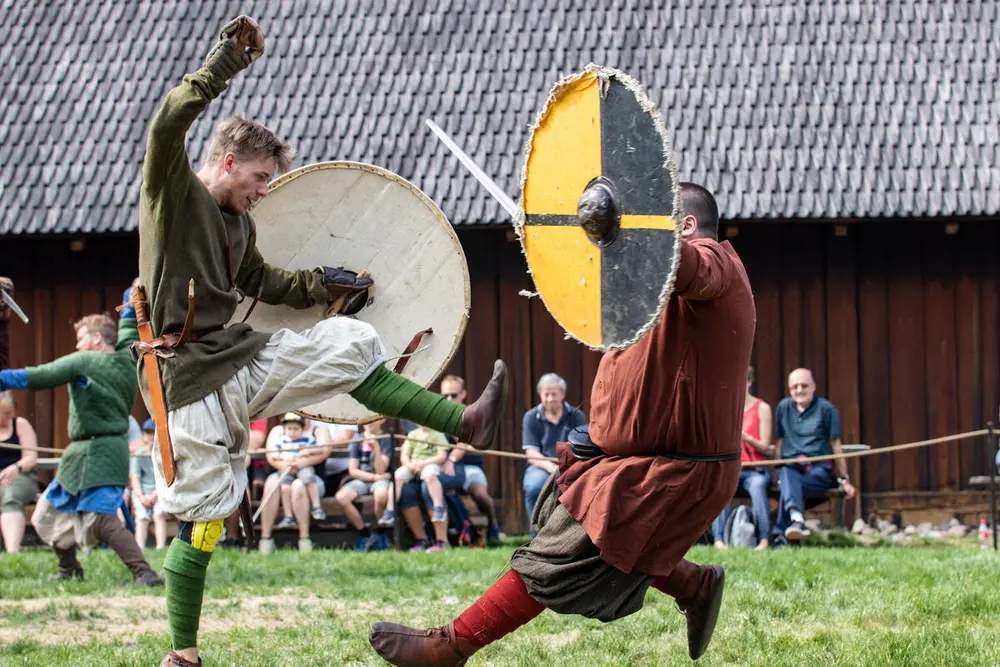 To menn kledd i vikingdrakter har kampleker utenfor Gildehallen