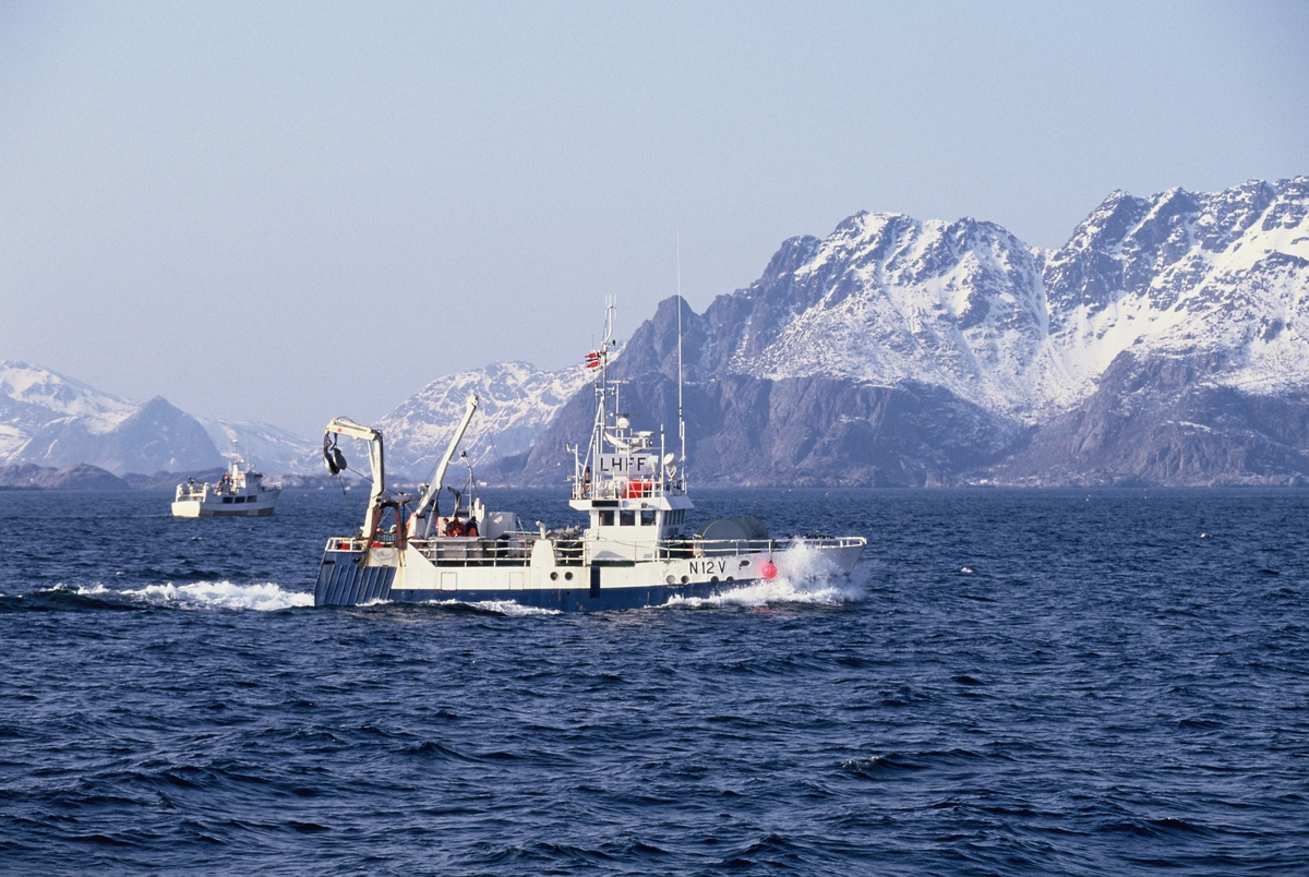 To fiskebåter på havet, Lofoten, med Lofotveggen i bakgrunnen