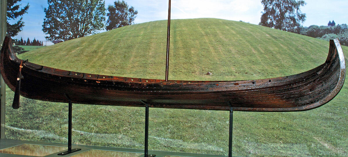Bildet viser en kopi av Osebergskipet foran gravhaugen. (Foto/Photo)