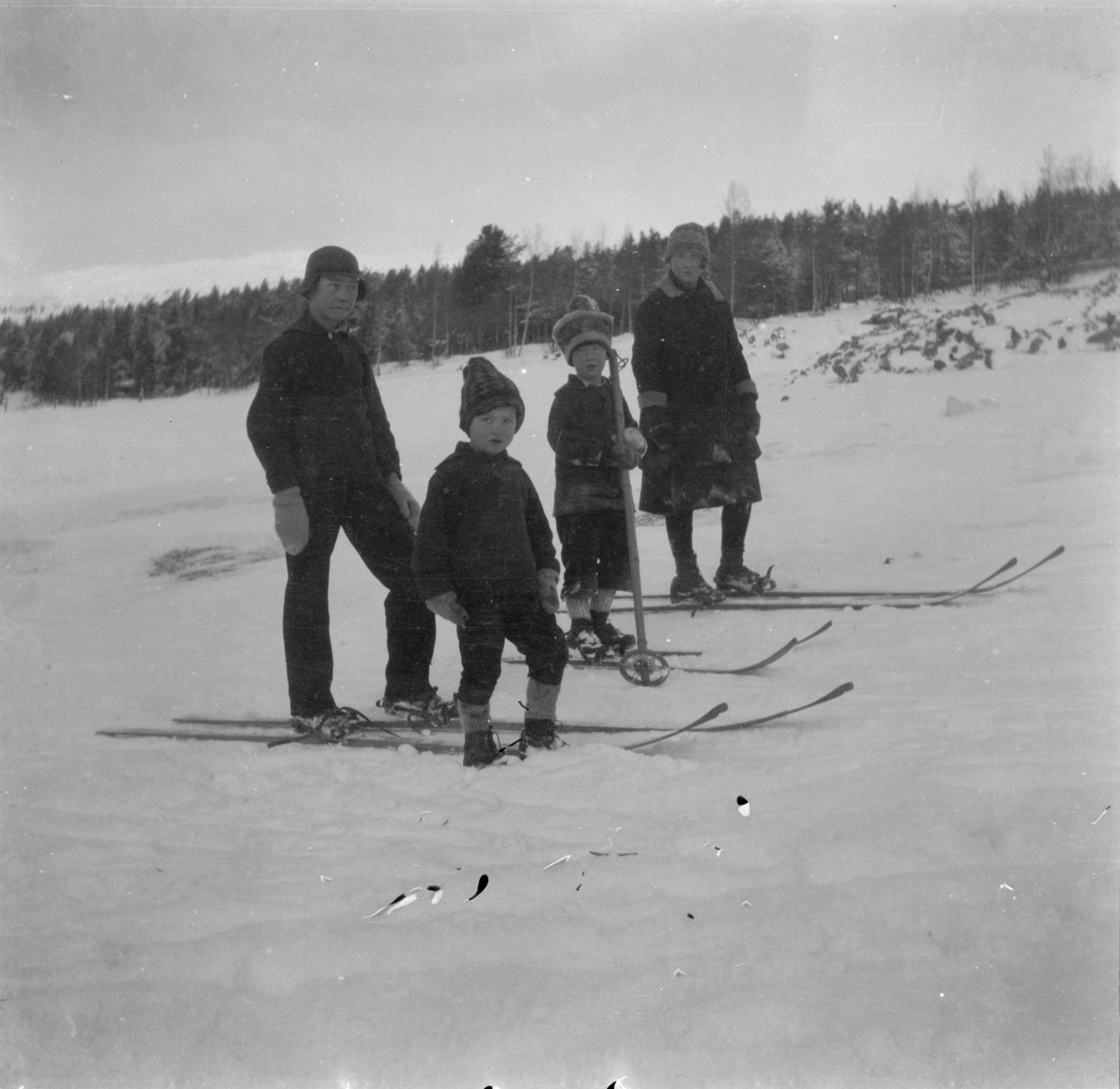 Ungene i Furuheim er ute på ski på et jorde med skog i bakgrunnen ...