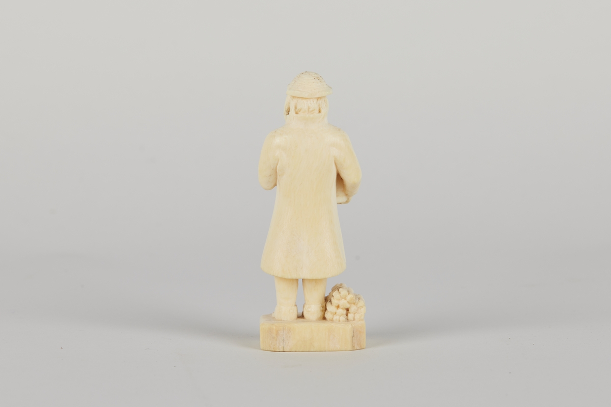 Mannsfigur med skjegg som holder et lagget kar under armen og har og et vedknippe ved føttene.