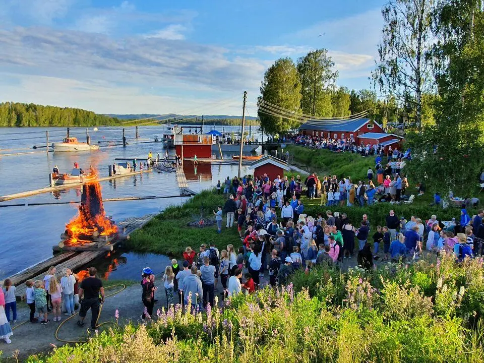 Foto av mange mennesker og bål ved elvebredden på Fetsund lenser