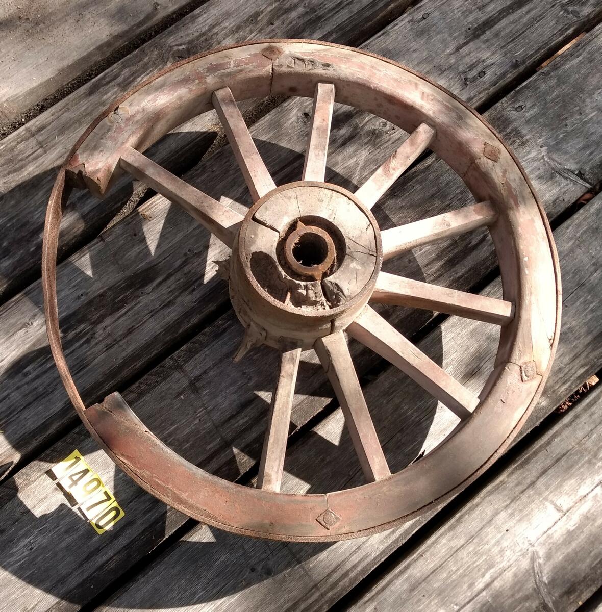 Rödmålat hjul med tolv ekrar, två tre saknas. Hel järnskoning runt nav och hjul. Hjulet / Löte är delat i sex delar med två ekrar. 1/6 av lötet saknas helt och 1/6 är skadad. Kan ev. vara MFF4141? De har bredd 63 cm. Plac: L1AA2.