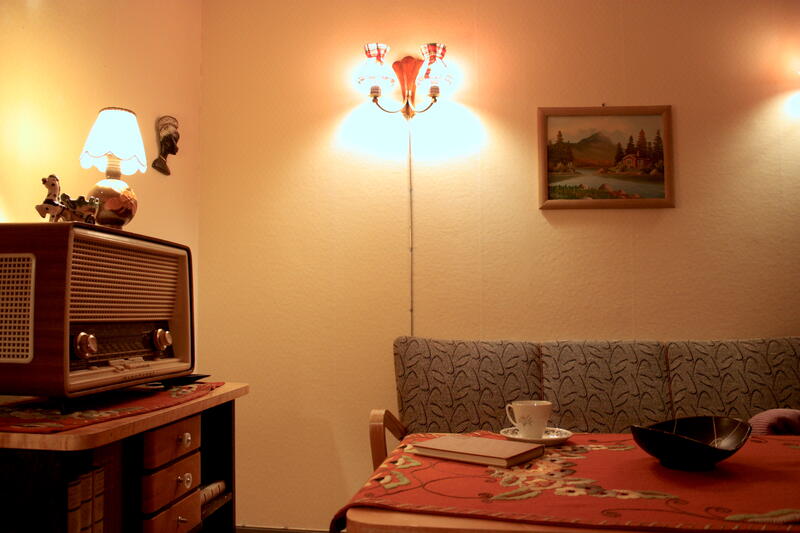 Utsnitt av stue i et gjenreisningshus, lampe, sofa, sofabord, radio