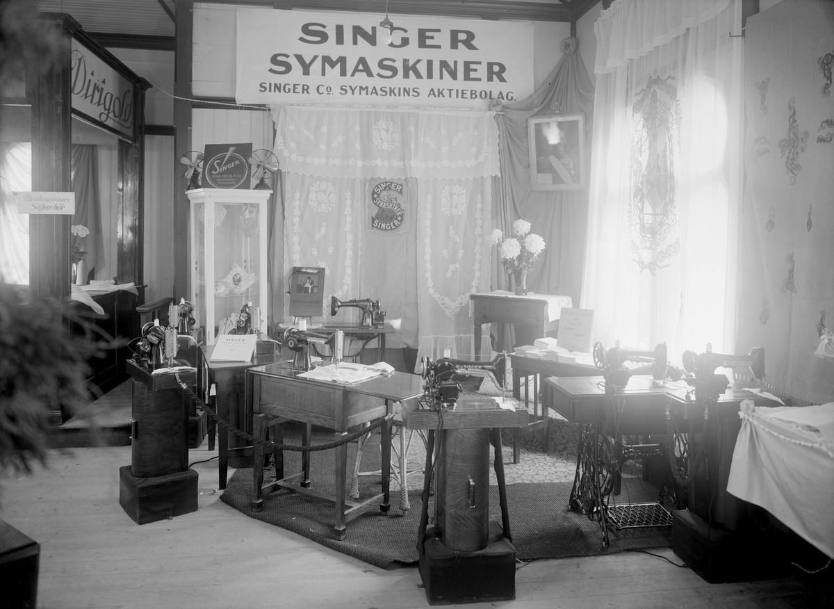 Vid middagstid fredagen den 24 oktober 1924 invigde Alice Trolle årets Hem- och Byggnadsutställning i Linköping. Platsen var Trädgårdsföreningens restaurang som samlat flertalet utställare med produkter på utställningens teman. Bilden visar Singers monter med det senaste inom maskinsömnad.