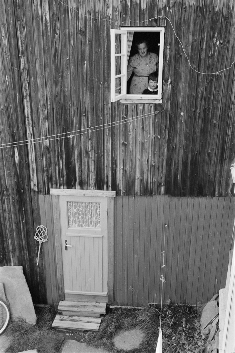 En kvinne og et barn står i et vindu på Røros.