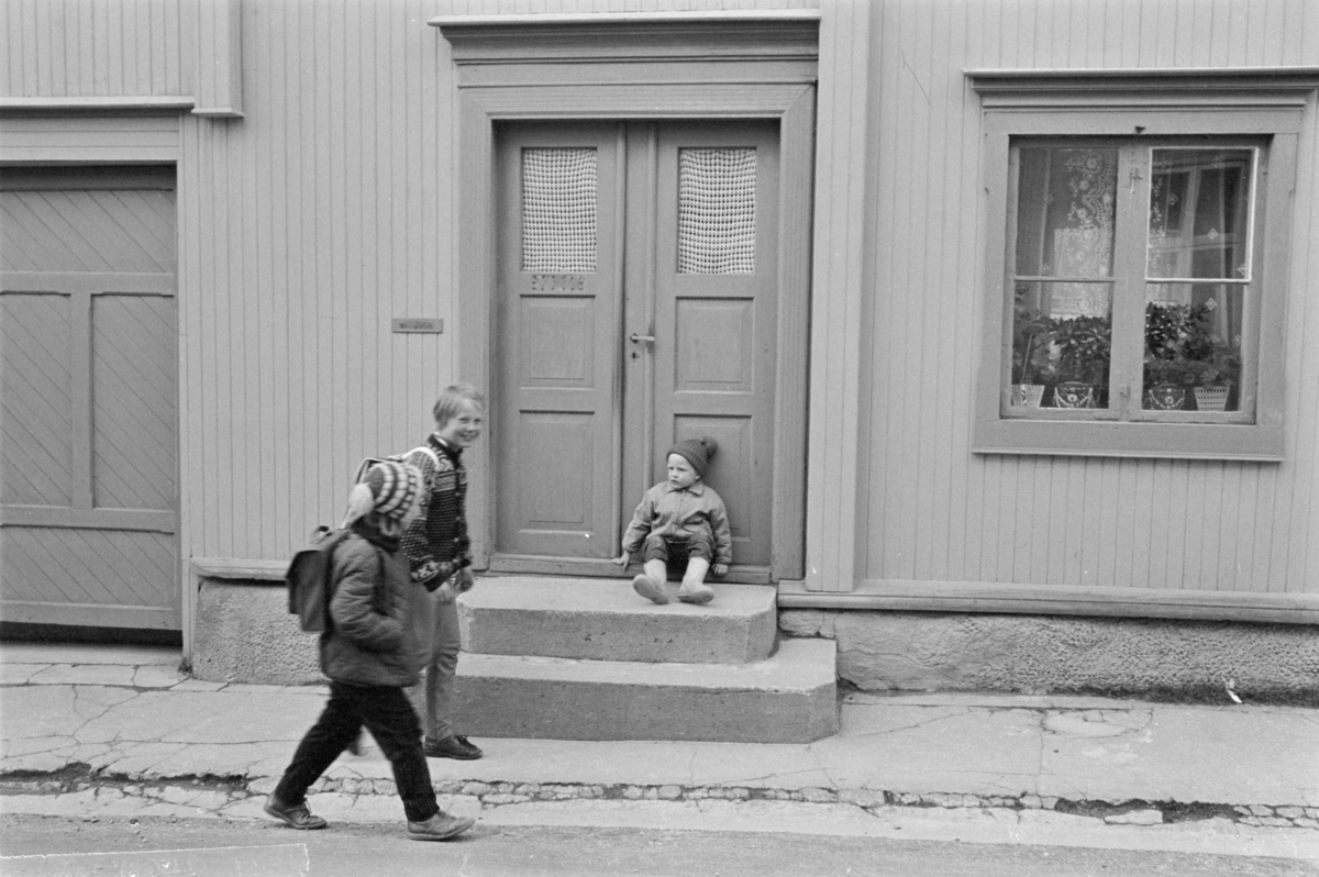 Et barn sitter på en trapp i en gate på Røros.