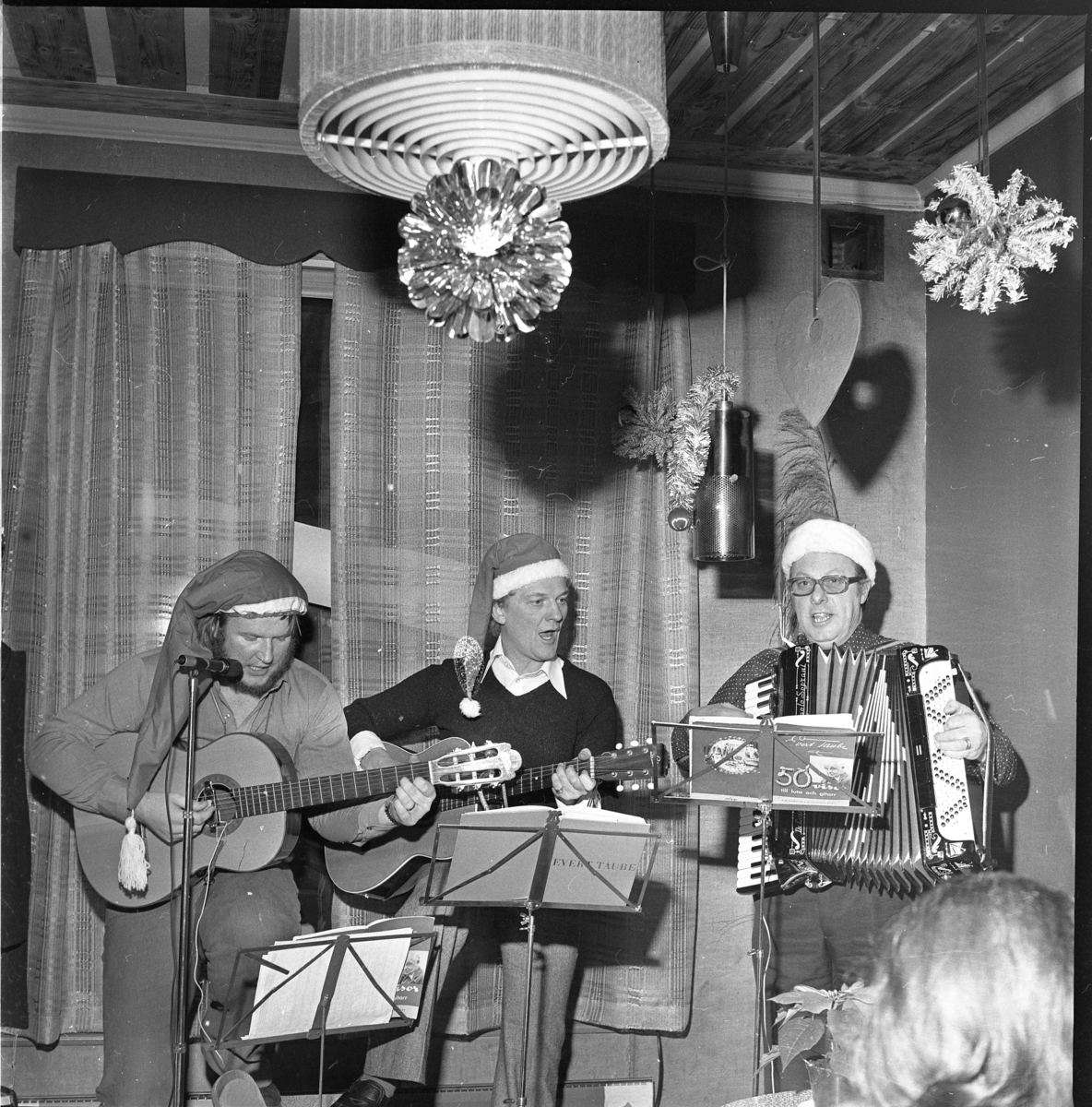 Tre män i tomteluva spelar och sjunger.