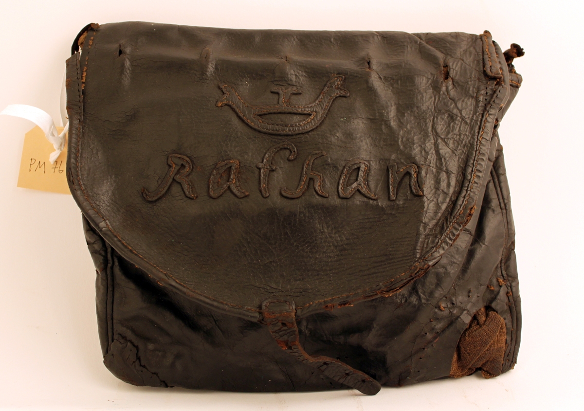 Lösväska, saknar bärrem. Klaffen är med sydda bokstäver i
läder: "Rathan" under krona. Under klaffen finns märken efter
låsanordning.