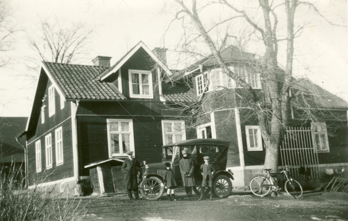 Exteriör av bostadshuset Solhem vid Malmen, omkring 1930-1940. En familj står framför en bil utanför huset.