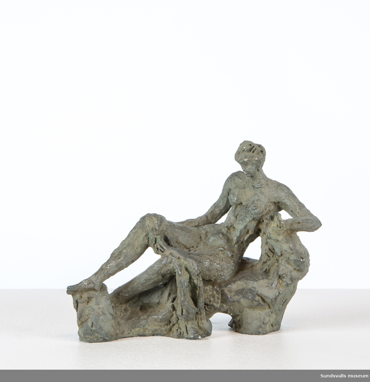 En skulptur i form av en sittande kvinna draperad med ett tygstycke.