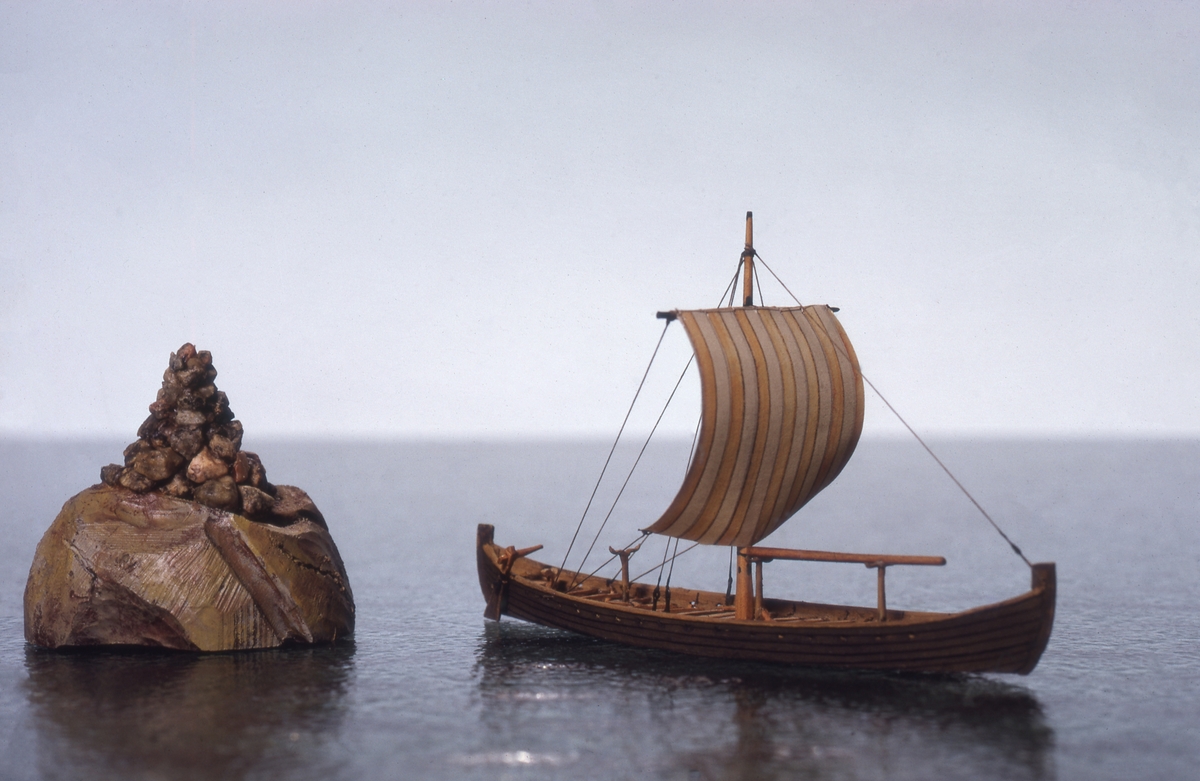 Fartygsmodell av trä. Vikingaskepp på vattenlinje. Sexton roddbänkar, styråra på styrbords sida. Riggad med en mast och ett röd-och vitrandigt segel av papper. Tältspira upplagd på bockar för om masten. Mörkbrun färg.
Skala 1:200Föremålets form: Vattenlinjemodell