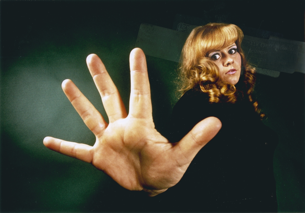 Foto av en kvinne som strekker hånden ut mot kameraet.