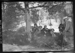 Gruppe menn på skitur koser seg med bål i skogen under et tr