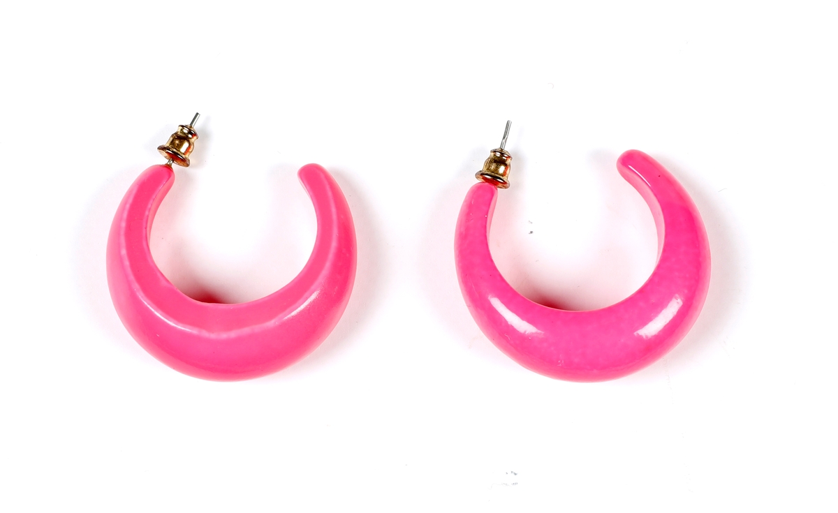 Et par rosa halvringer i rosa plast med metallstift.  Smales i hver ende og bredest på midte. Litt tunge.