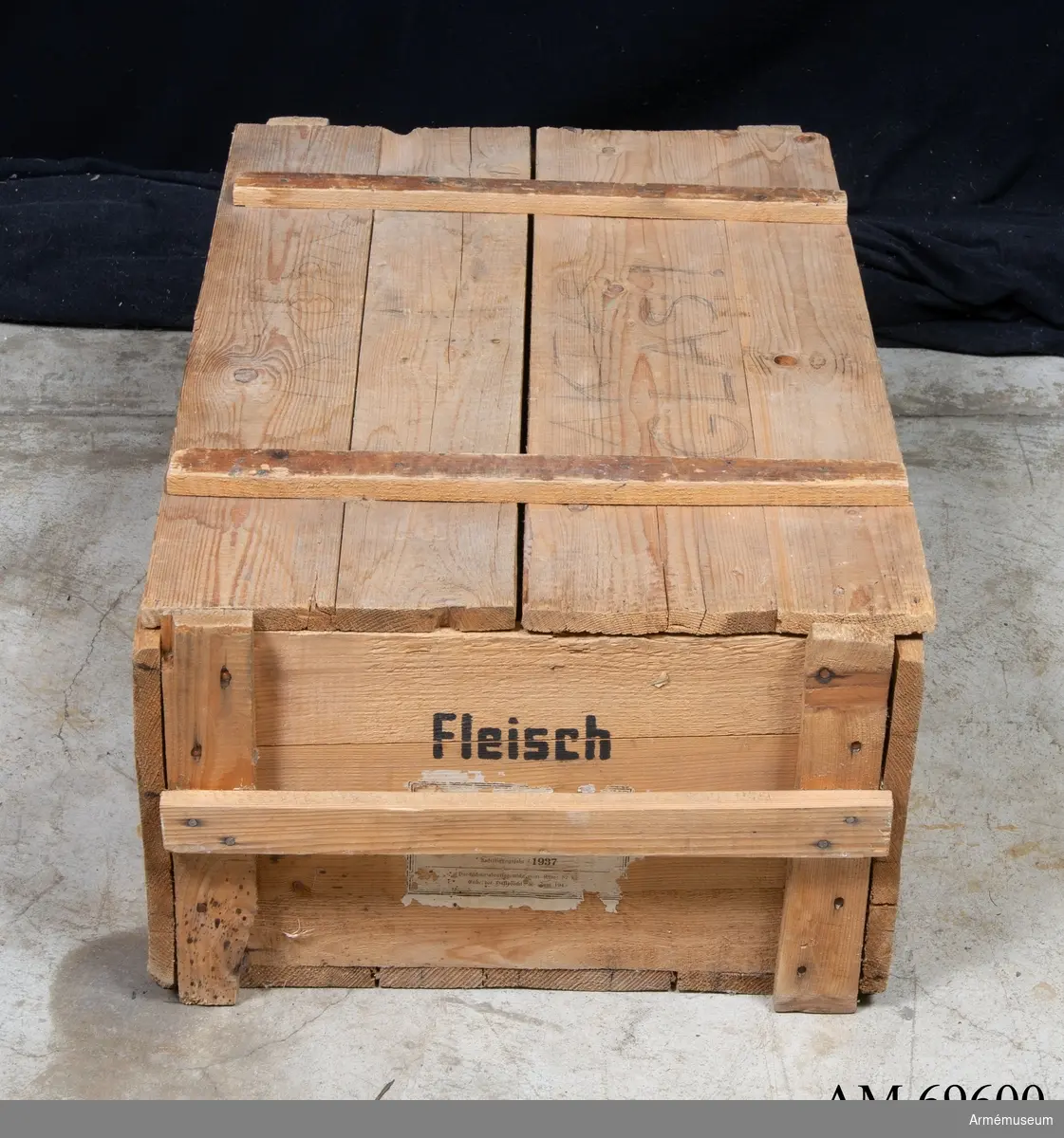 Låda av trä märkt med texten "Fleisch" i svart samt etiketter med tyskt text och årtalet 1937. I lådans botten finns spår av runda ringar.