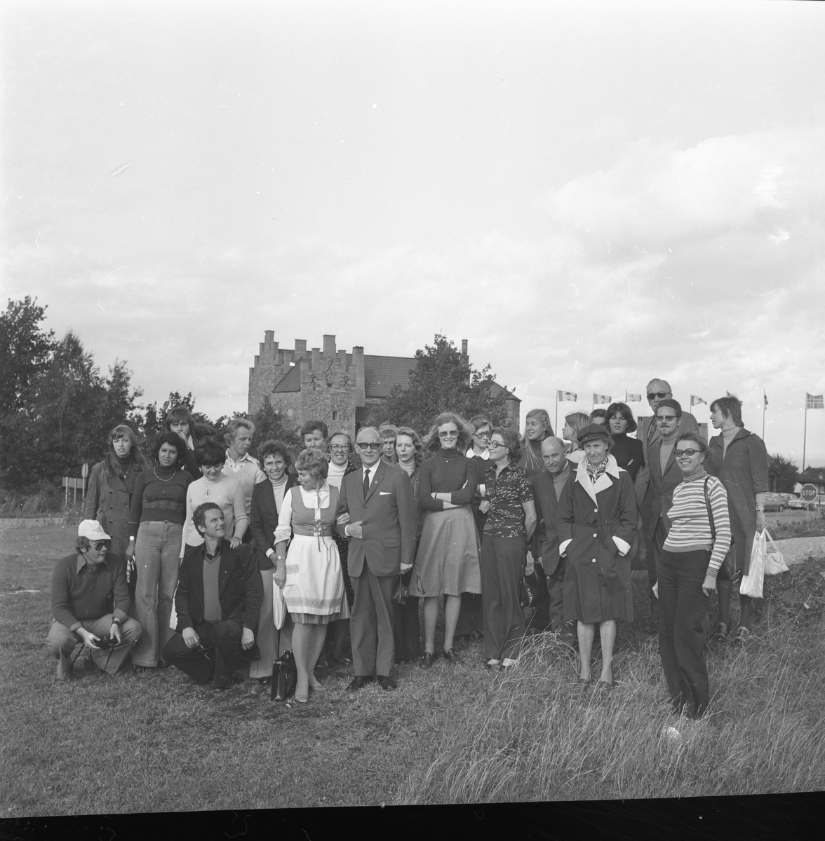 Gruppbild med kvinnor och män på en gräsplan med Gyllene Uttern i bakgrunden.