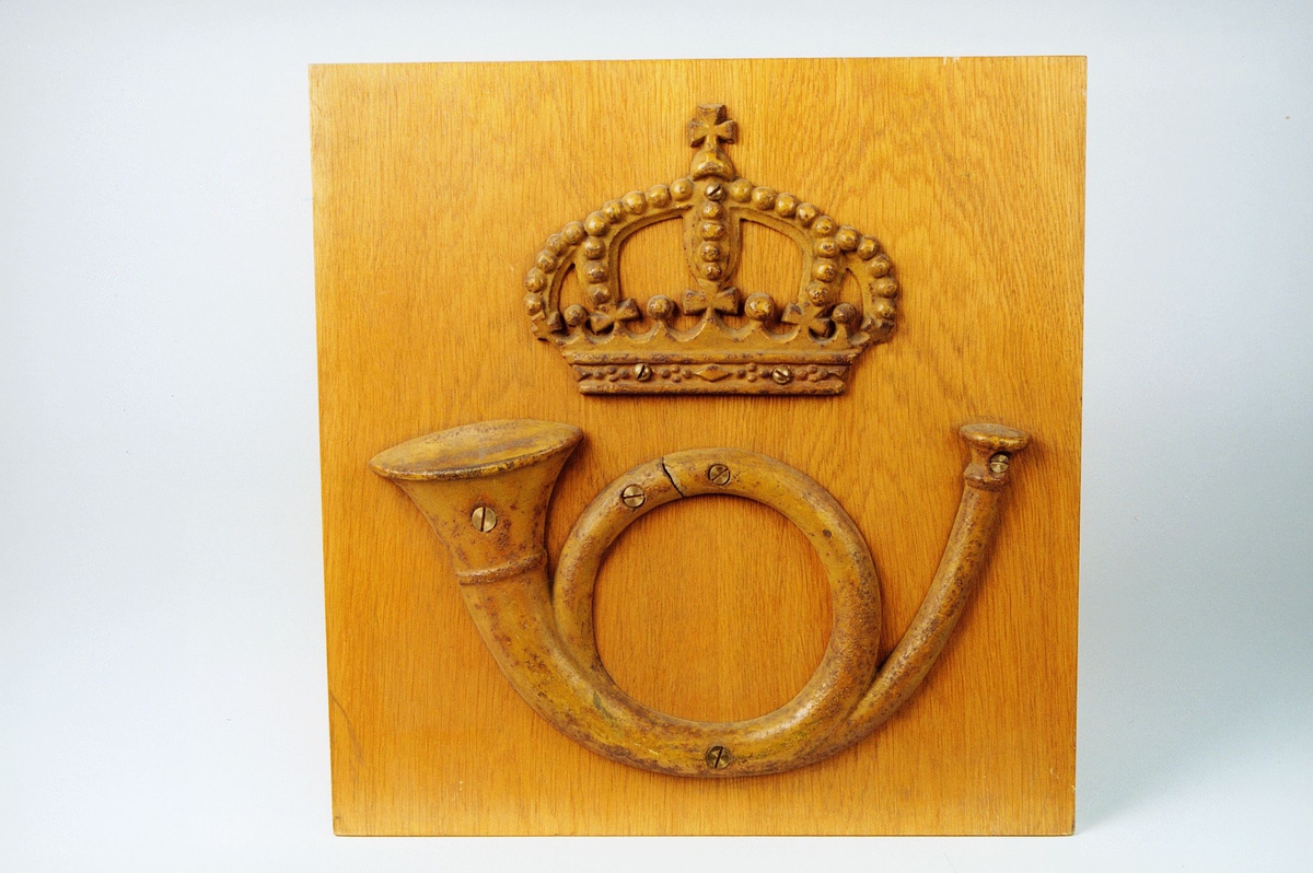 Postmuseet, gjenstander, skilt, postskilt, posthorn og krone (postlogo) montert/skrudd fast på en treplate.
