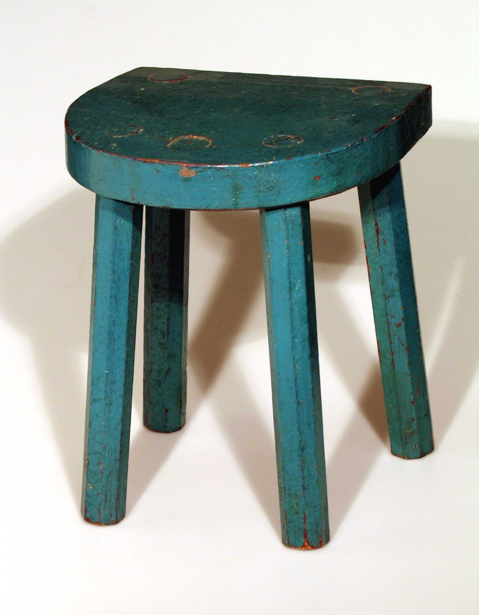 Peiskrakk med fire bein malt blågrønn. Setet er halvsirkelformet. Benene er åttekantet.