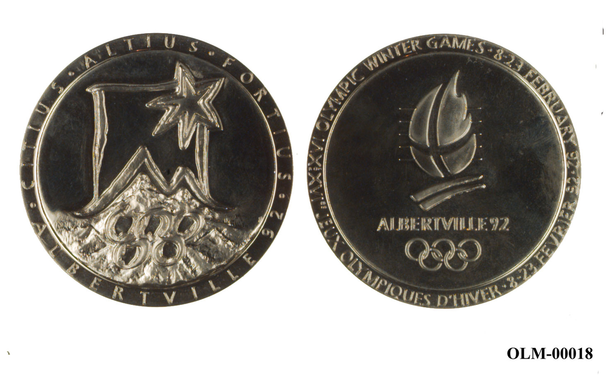 Sølvfarget minnemedalje med emblemet for de olympiske vinterleker i Albertville i 1992 og motiv av en stjerne over alpene og de olympiske ringene. 