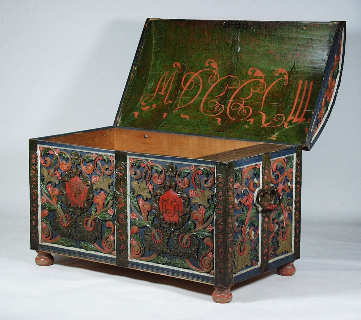 En kiste i furu med akantusskurd og er malt i blå bunnfarge. Kisten har også jernbeslag med uthamret ranker på hver kant og på midten av kisten. På fronten av kisten blir innskriften rammet inn av akantuskranser.