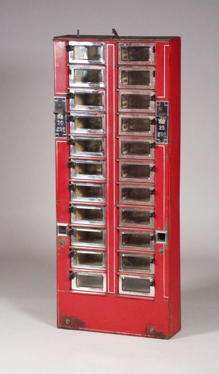 Rød sjokoladeautomat i metall med glassluker i to høyder, en for 30 og en for 25 øre. Lukene har krom innramming, og håndtakene er laget i bakelitt. 