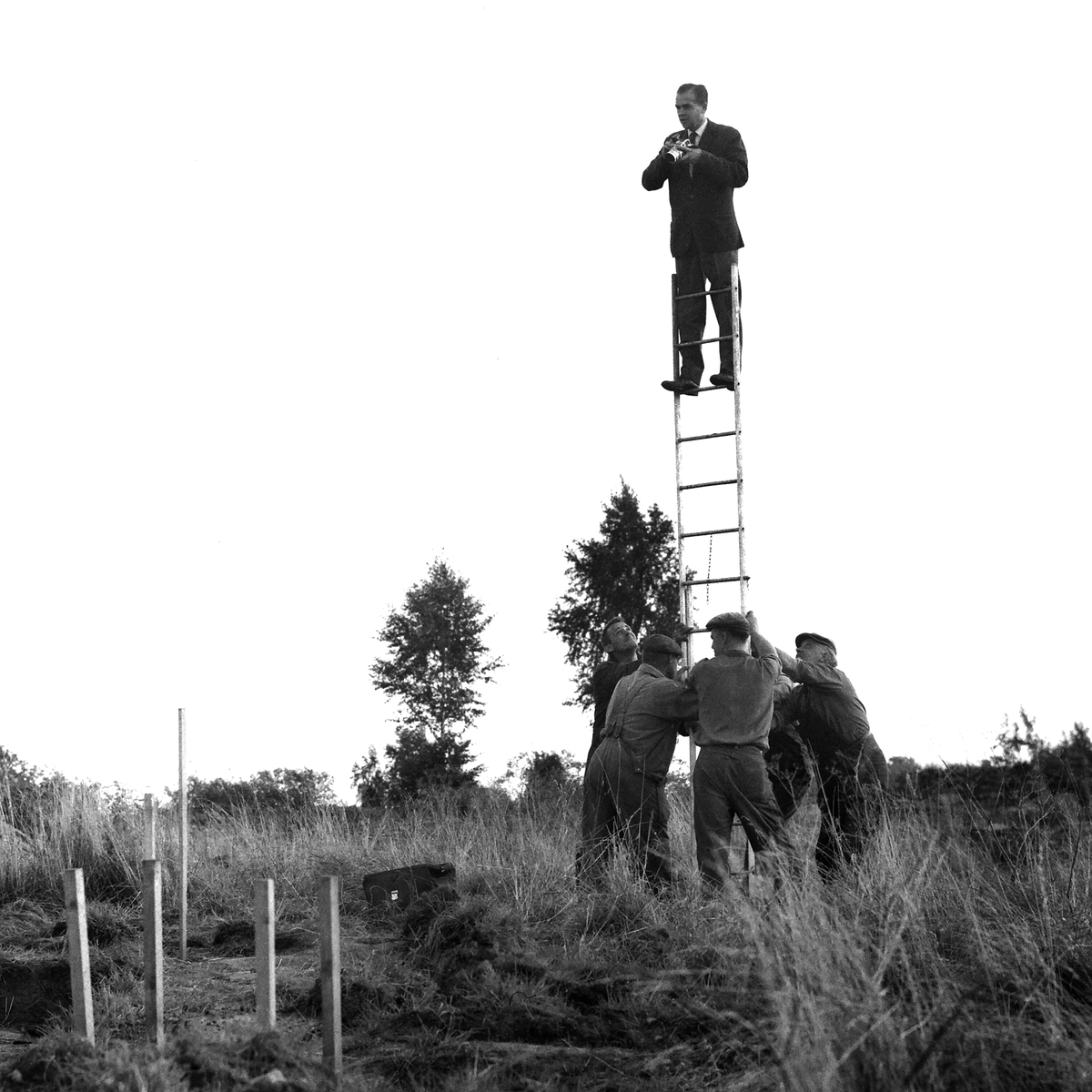 Allt för en bra bild. Vid en arkeologiskt undersökning i Linköpingstrakten krävdes det redskap och handräckning för att nå rätt perspektiv. Fotograf Arne Gustafsson på uppdrag 1962.