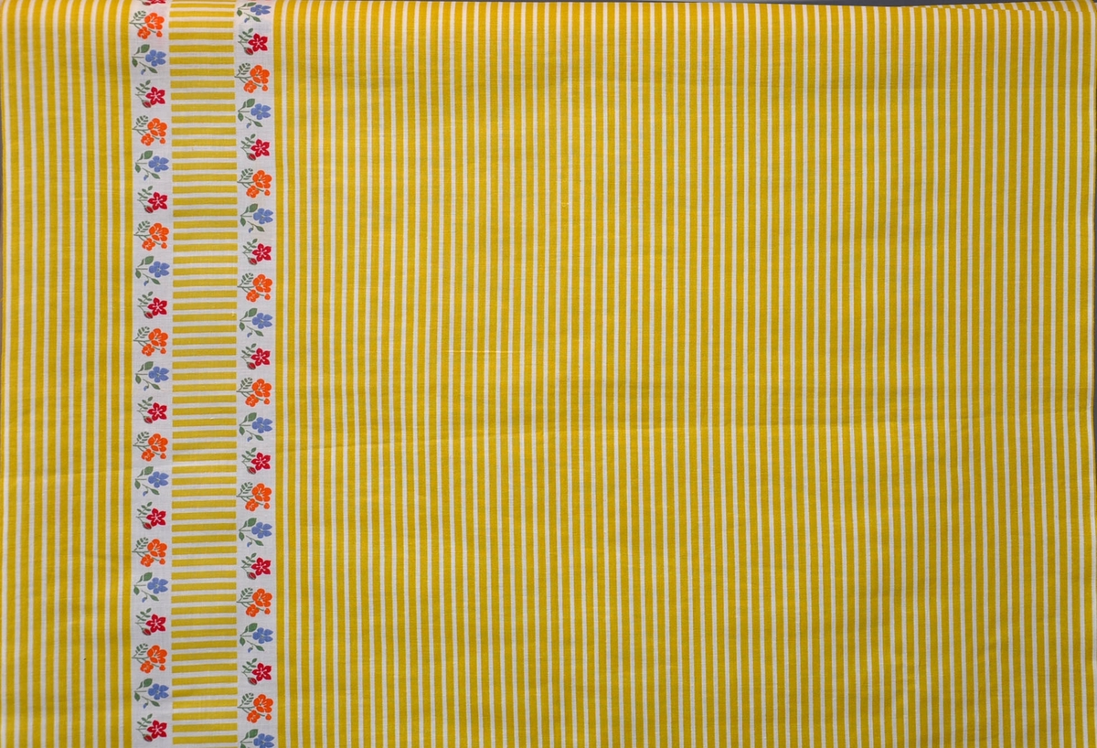 Bomullstyg, 1950-talet. Design Kerstin Persson.
Förklädestyg Edit på 70 cm bredd.
Ränder i gult på vit botten längs och tvärs med 2 bårder med  små blombuketter och tvära ränder som bård i ena sidan.
Rapport 6,5 x 69,5 cm
Antal tryckfärger 5