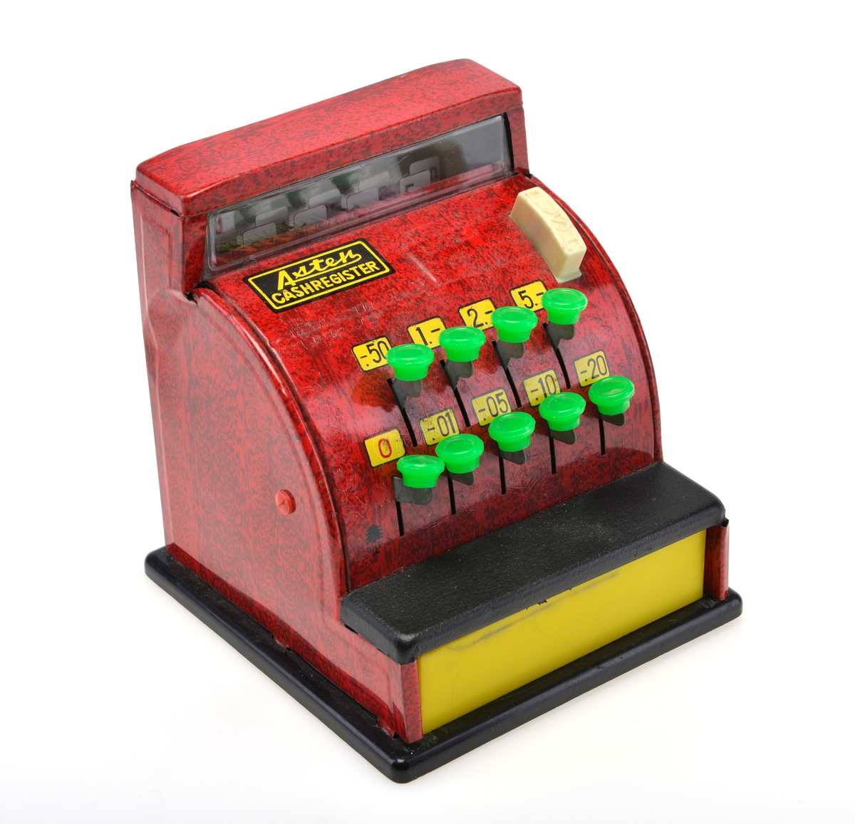 Rødt lekekasseapparat i tinn. Apparatet har flere grønne knapper som lar en velge priser for "varer". Den hvite "PUSH" knappen skal åpne den gule skuffen og lage en bjellelyd, men denne funksjonen fungerer ikke grunnet gjenstandens tilstand. Apparatet har opprinnelig hatt mynter som fulgte med.