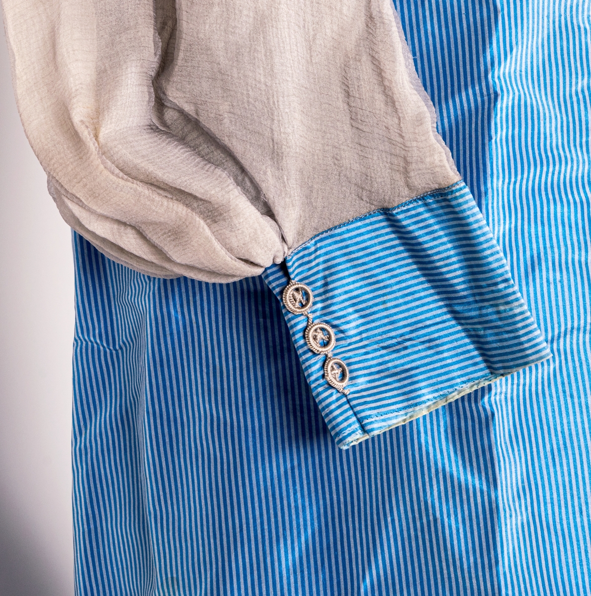 Blå sidenklänning med spetskrage och tyllärmar. Klädda blyvikter monterade för att ge klänningen rätt fall.