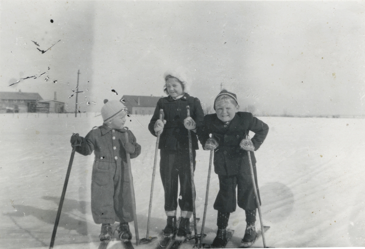 Tre blide barn ute på skitur.