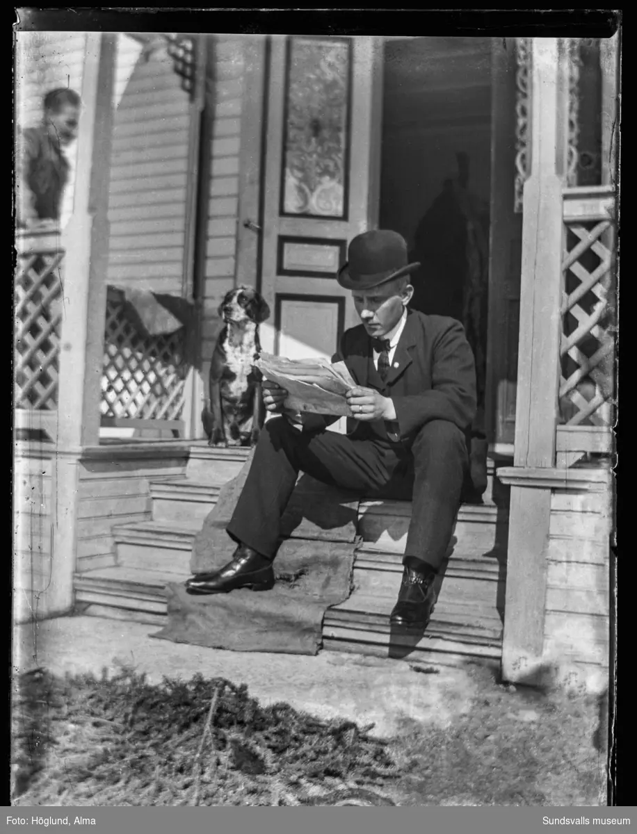 Gottfrid Höglund sitter på trappen till hemmet i Fanbyn och läser tidningen. En hund sitter intill.