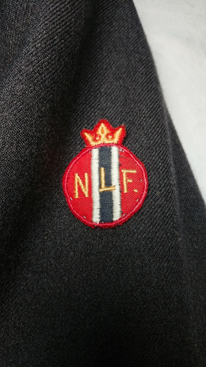 Merkene for Norges Lotteforbund og Heimevernet er fastsydd på henholdsvis venstre og høyre jakkeerme. Jakka har fôr.