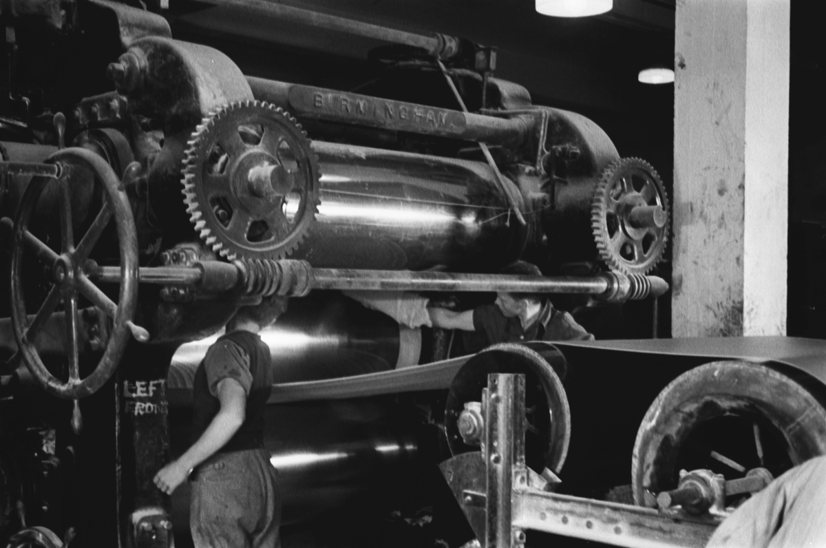 Askim Gummivarefabrikk A/S, her et blikk inn i maskinens indre, til høyre i bildet skimter vi ansvarlig industriarbeider.