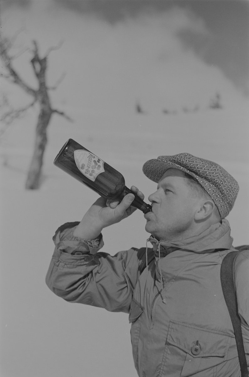 Påsketurist på ski tar seg en Pilsner-Øl. Fotografert 1940.