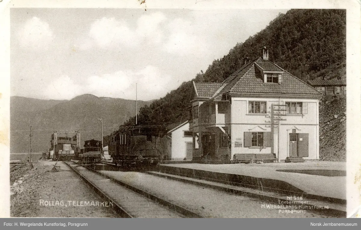 Rollag (Mæl) stasjon på Rjukanbanen. I bakgrunnen DF Rjukanfos, i spor 1 på stasjonen to personvogner