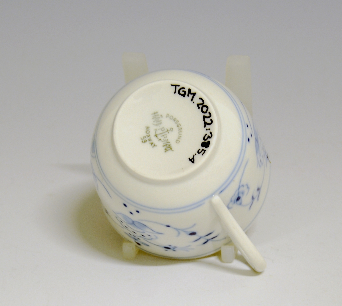 Kaffeskål i porselen. Dekorert med håndmalt stråmønster i blått. 

Dekor: "Porsgrunnsmønsteret", variant av stråmønster, antagelig av Hans Flygenring.