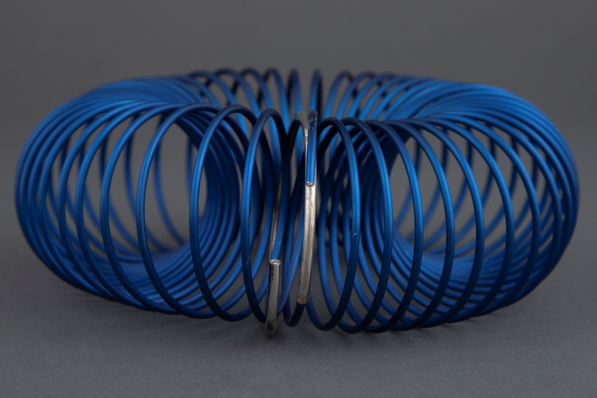 Armsmykke satt sammen av en spiral av blått eloksert aluminium. Ett ledd i spiralen er uført i sølv. Smykket er mykt og føyer seg etter håndleddet, men beholder samtidig sin form.