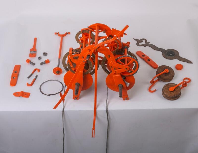 En haug med oransje metalldeler som tilsammen utgjør et urverk laget av Abraham Pihl.