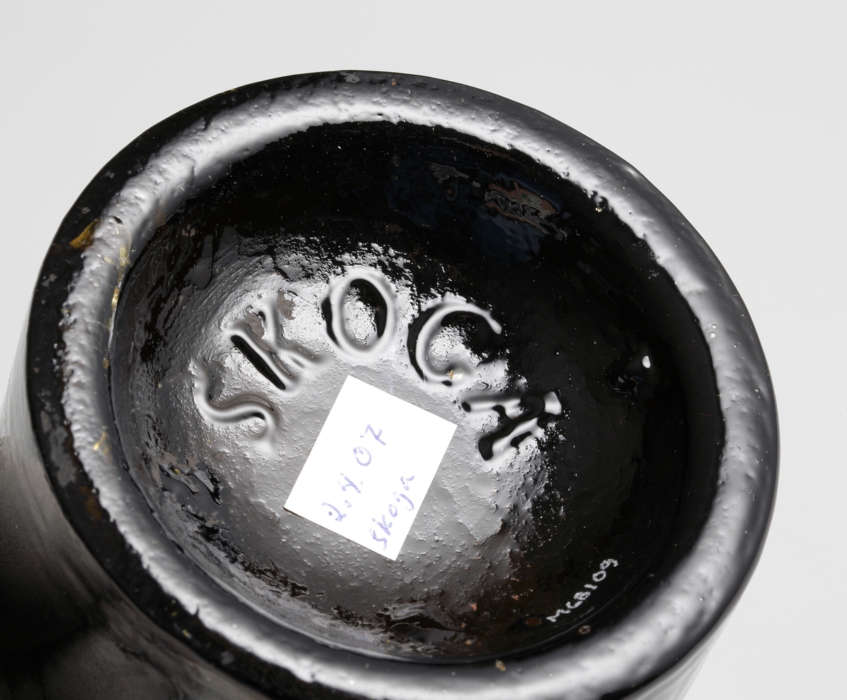 Brun flaskbotten av engelsk modell, tillverkad i tredelad järnform på Skoga glasbruk.
